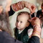 A baby's first haircut performed during a religious ritual with parents and clergy present.