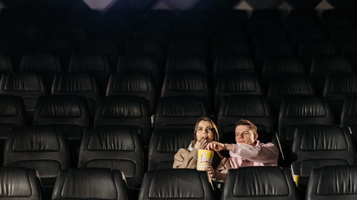 A couple enjoying a movie date with popcorn in an empty theater.